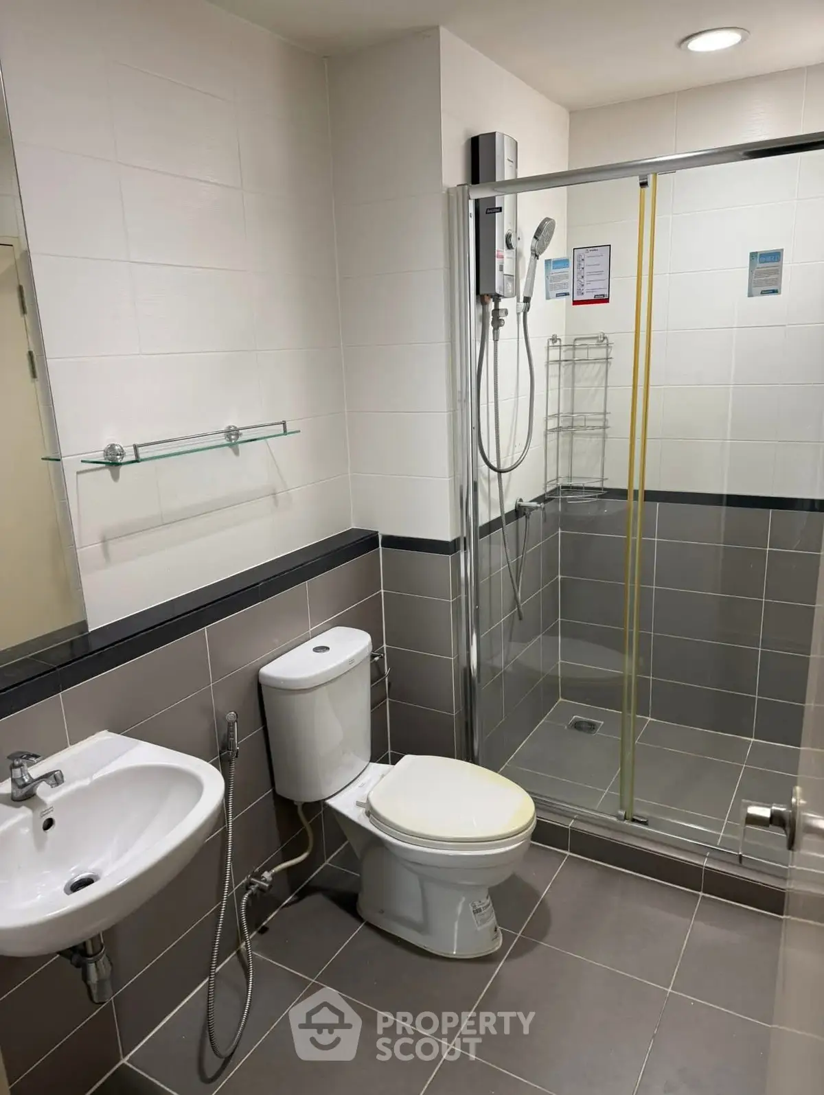 Modern bathroom with glass shower and sleek fixtures in contemporary apartment.