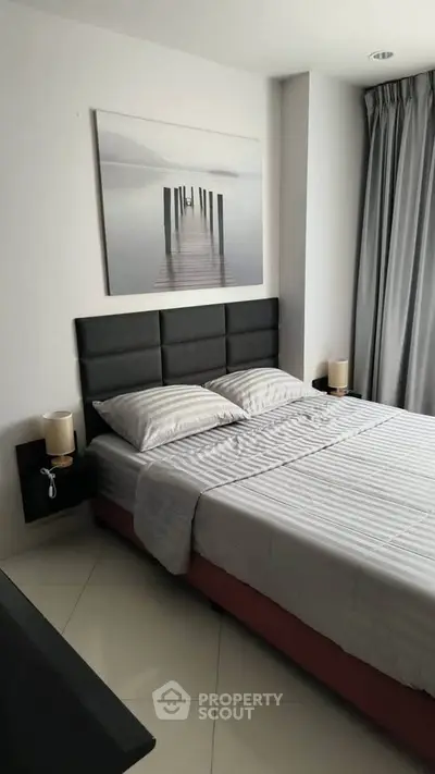 Modern bedroom with stylish decor and natural light, featuring a comfortable bed and elegant artwork.