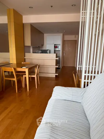 Spacious open-plan living room with wooden flooring and modern kitchen in a stylish apartment.