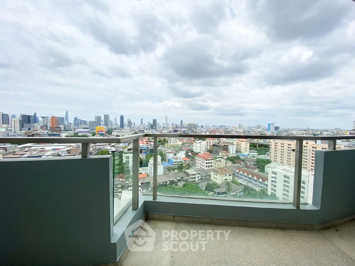 Stunning cityscape view from a high-rise balcony with glass railing, perfect for urban living.