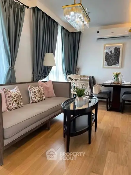 Elegant living room with chic decor and dining area, featuring hardwood floors and stylish lighting.