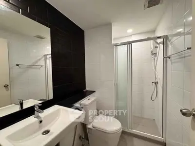 Modern bathroom with sleek fixtures and glass shower enclosure in a contemporary apartment.