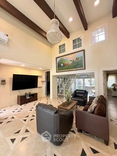 Luxurious living room with high ceilings, elegant chandelier, and modern decor in a spacious home.