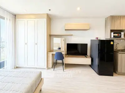 Modern studio apartment with sleek furnishings and city view, featuring a cozy bed, TV, and compact kitchen.