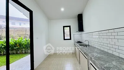 Modern kitchen with sleek countertops and garden view, featuring gas stove and open layout.