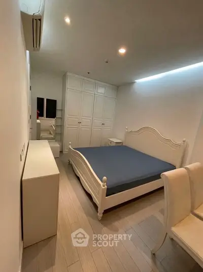 Spacious bedroom with elegant white furniture and ample storage space.