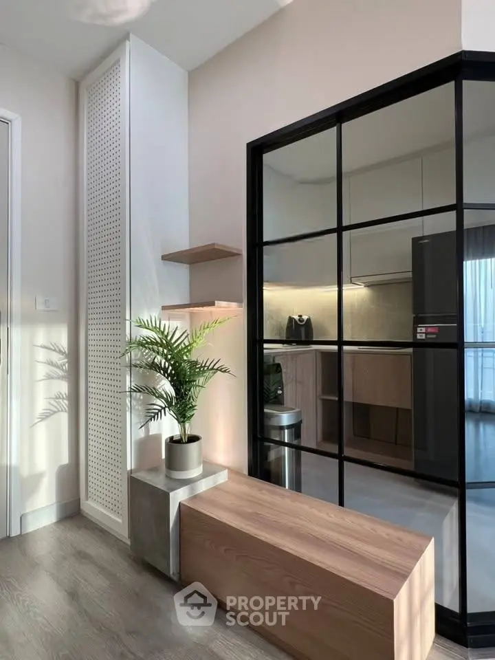 Modern interior with sleek kitchen and stylish decor, featuring glass partition and wooden accents.