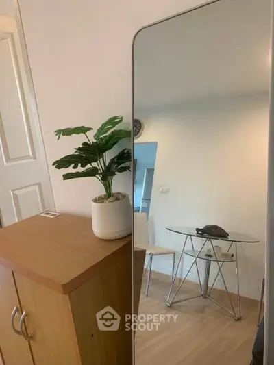 Modern interior with stylish mirror, wooden cabinet, and glass table in a cozy living space.