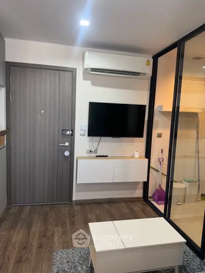 Modern living room with wall-mounted TV and air conditioning in a stylish apartment.