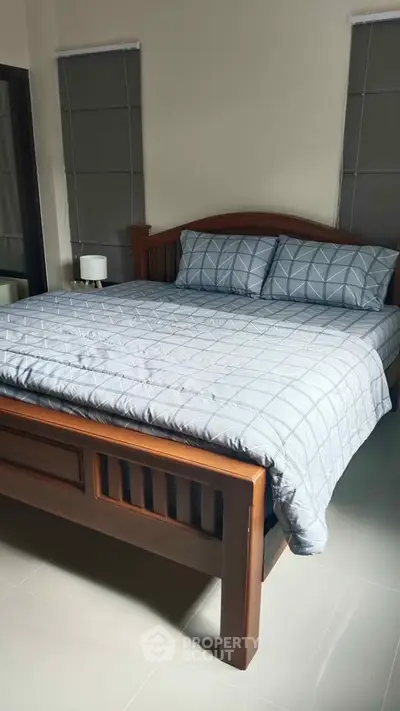 Cozy bedroom with wooden bed frame and soft bedding in a serene setting.