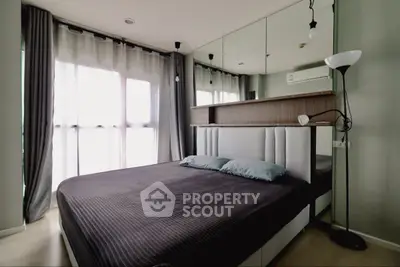 Modern bedroom with stylish decor, large window, and mirrored wall for spacious feel.
