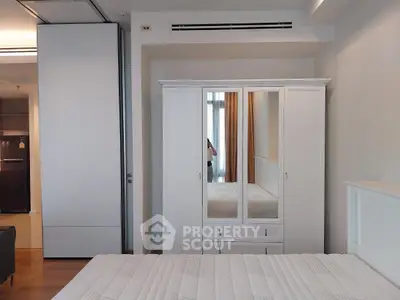 Modern bedroom with white wardrobe and comfortable bed in stylish apartment