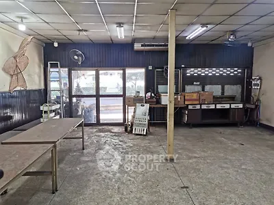Spacious industrial-style room with large windows and metal tables, ideal for workshop or creative space.