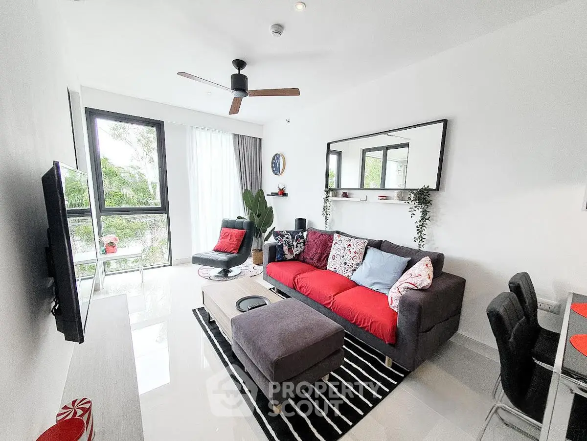 Modern living room with stylish decor, large window, and vibrant red sofa in a contemporary apartment.