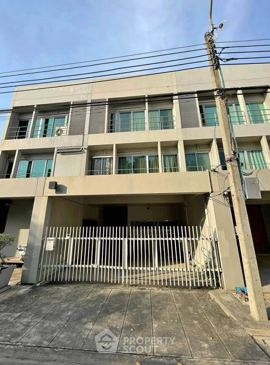 Modern multi-story building with gated entrance and large windows, ideal for urban living.