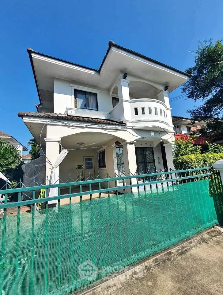 Charming two-story house with a spacious balcony and lush garden, perfect for family living.