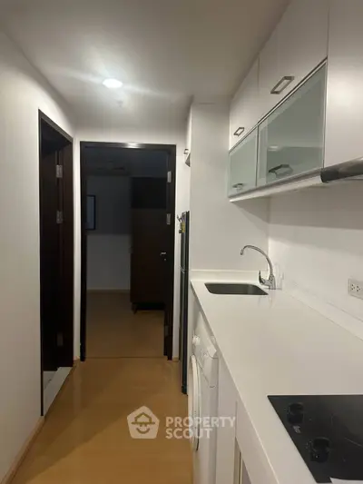 Modern kitchen with sleek white cabinetry and built-in appliances in a compact apartment.
