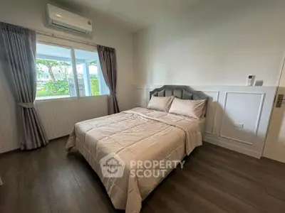 Cozy bedroom with elegant decor and large window offering garden view