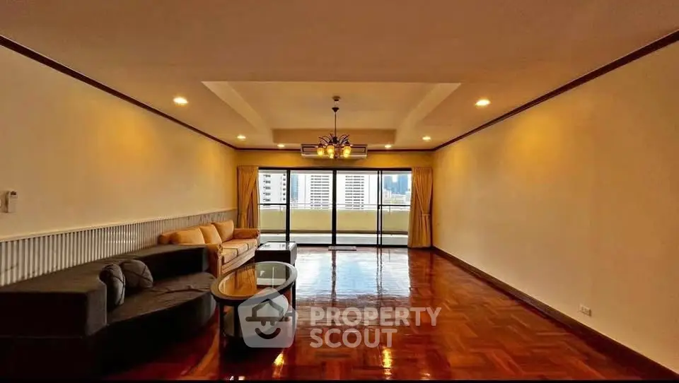 Spacious living room with polished wooden floors and city view balcony.