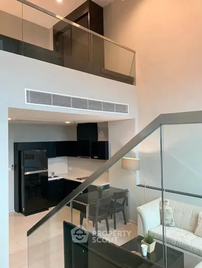 Modern duplex apartment with sleek kitchen and stylish living area, featuring glass railings and high ceilings.