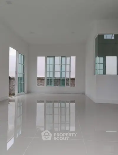 Spacious empty room with large windows and glossy tiled floor