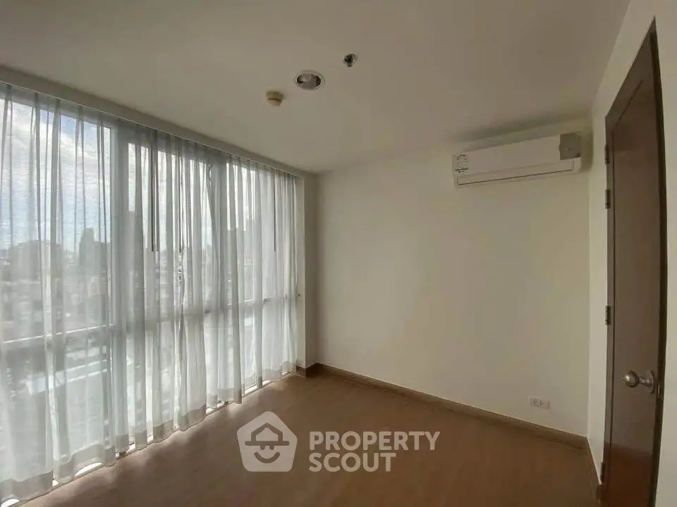 Bright empty room with large windows and air conditioning, perfect for customization.