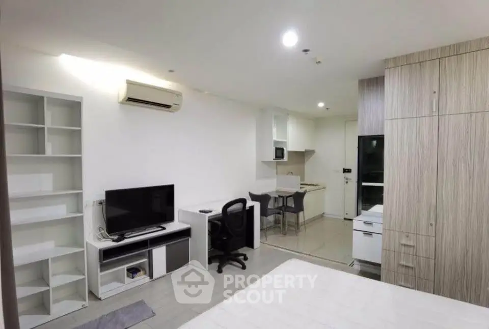 Modern studio apartment with open layout, featuring a cozy living area, compact kitchen, and sleek furnishings.
