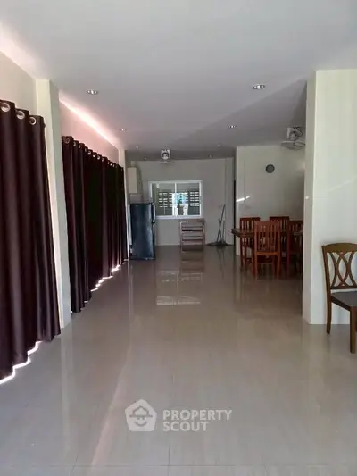 Spacious open-plan living area with dining set and modern kitchen appliances, perfect for family gatherings.