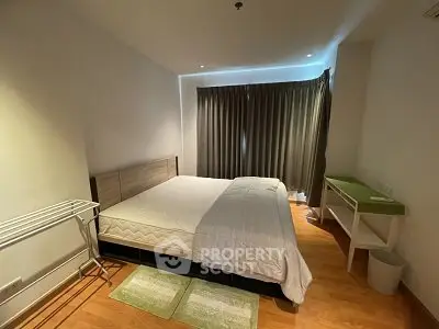Spacious bedroom with modern furnishings and wooden flooring, featuring a large bed and ample natural light.
