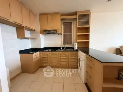 Modern kitchen with wooden cabinets, black countertops, and built-in washing machine.