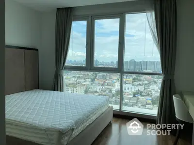 Spacious bedroom with stunning city view from large windows, modern decor and natural light.