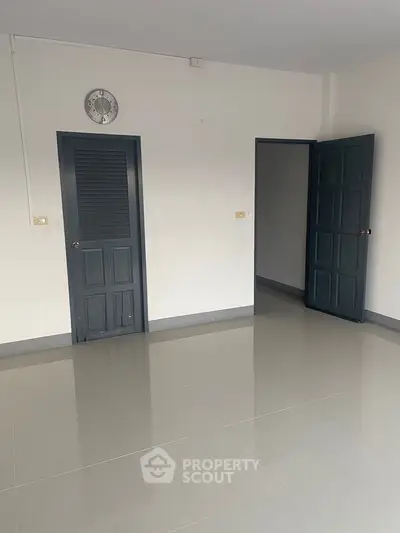 Spacious empty room with tiled flooring and dark doors, ready for customization.
