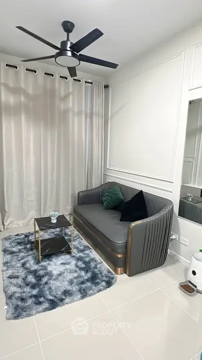 Modern living room with stylish sofa, elegant curtains, and sleek ceiling fan in a cozy setting.