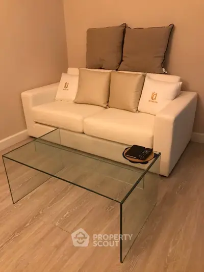 Cozy living room with modern white sofa and elegant glass coffee table.