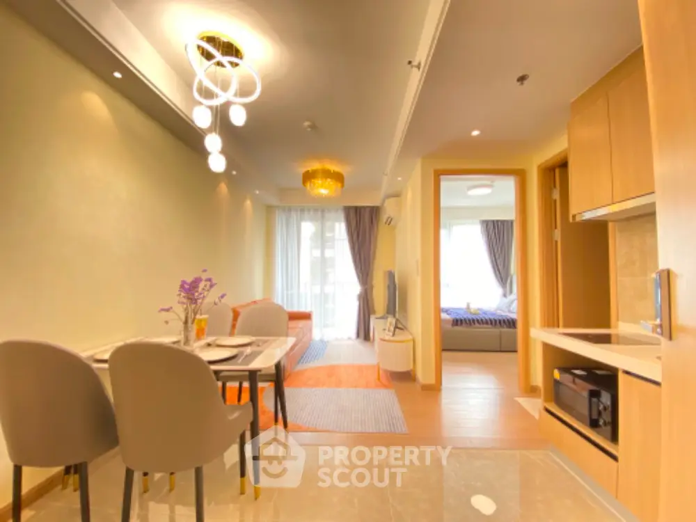 Modern open-plan living and dining area with elegant lighting and cozy bedroom view.