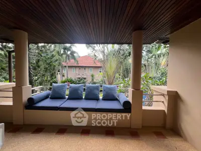 Charming balcony with cozy seating and lush garden view in tropical setting.