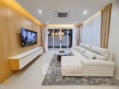 Modern living room with elegant decor, featuring a large sectional sofa, wall-mounted TV, and ambient lighting.