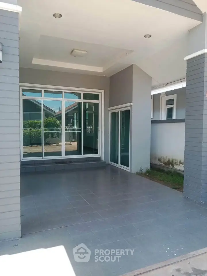 Modern house exterior with spacious tiled patio and large windows