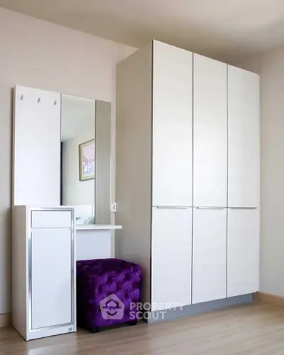 Modern bedroom with sleek white wardrobe and stylish purple ottoman