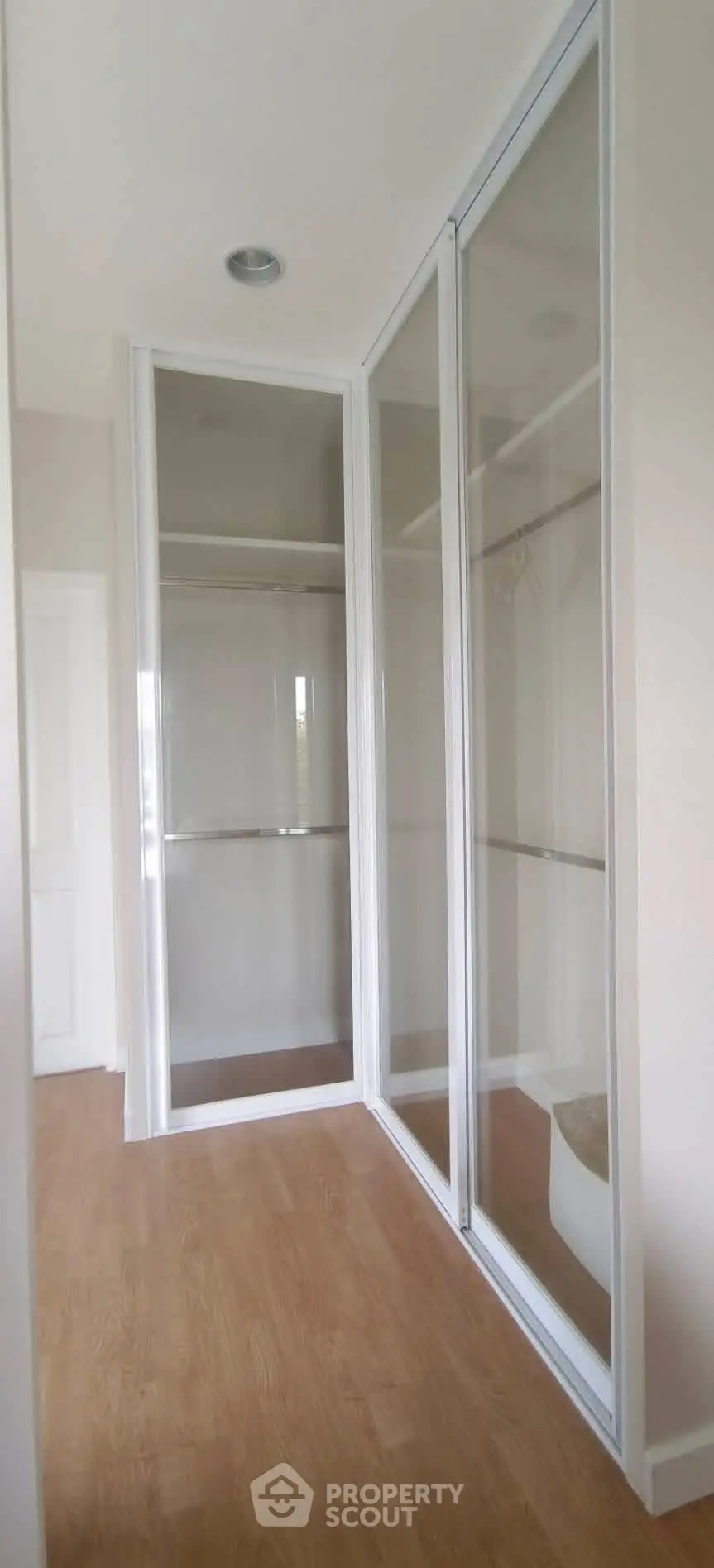 Spacious walk-in closet with mirrored sliding doors and wooden flooring