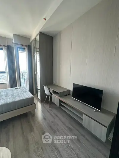 Modern bedroom with sleek design, featuring a bed, desk, and large window with city view.