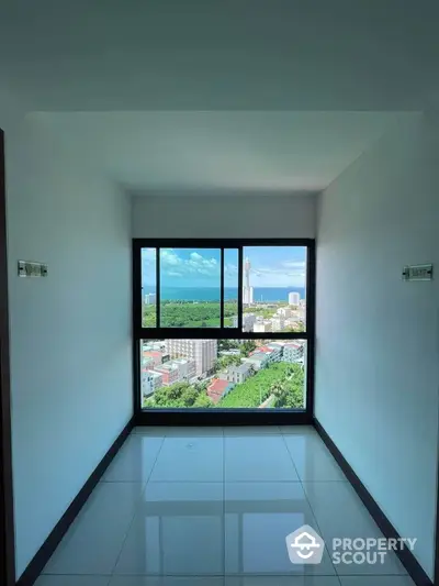 Stunning high-rise view of cityscape and ocean from modern apartment window.