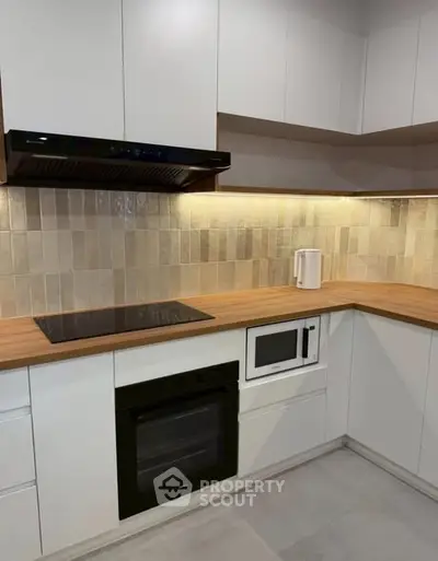 Modern kitchen with sleek cabinetry and built-in appliances, featuring a stylish backsplash and wooden countertops.