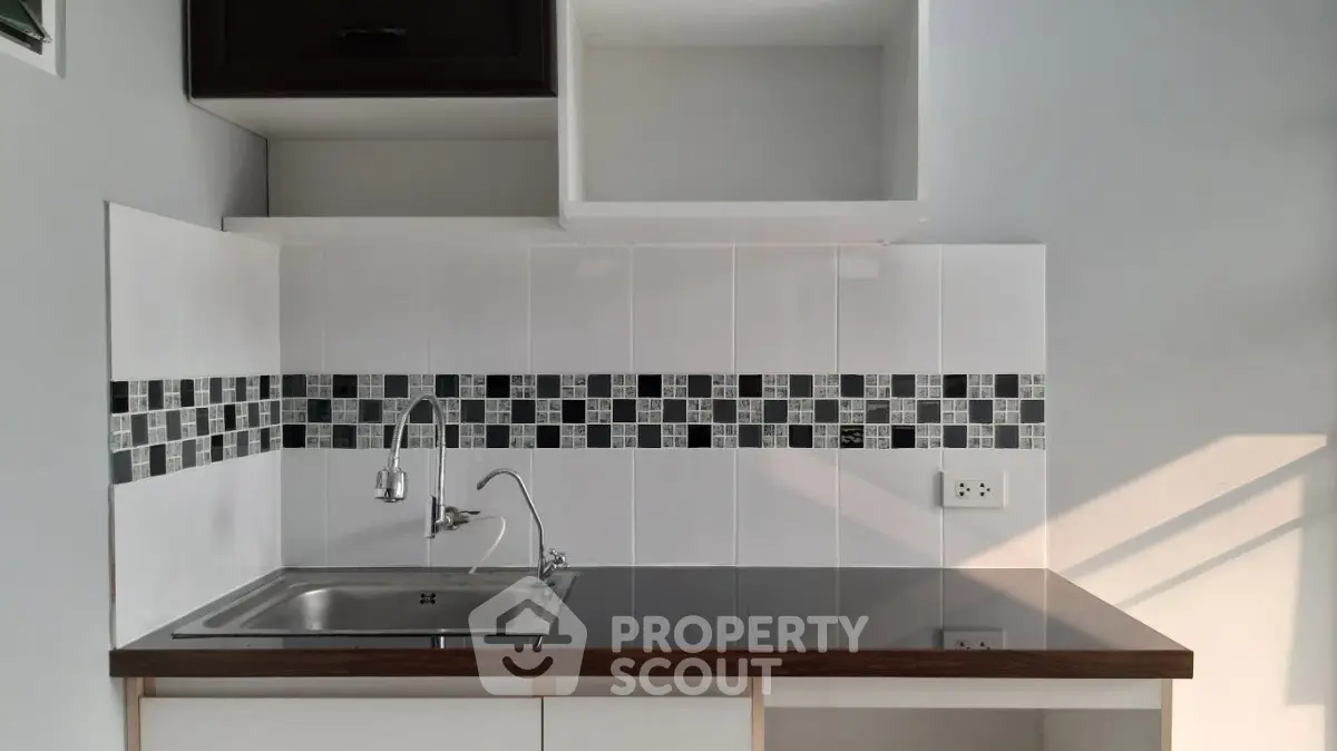 Modern kitchen with sleek countertop and stylish backsplash in contemporary apartment.