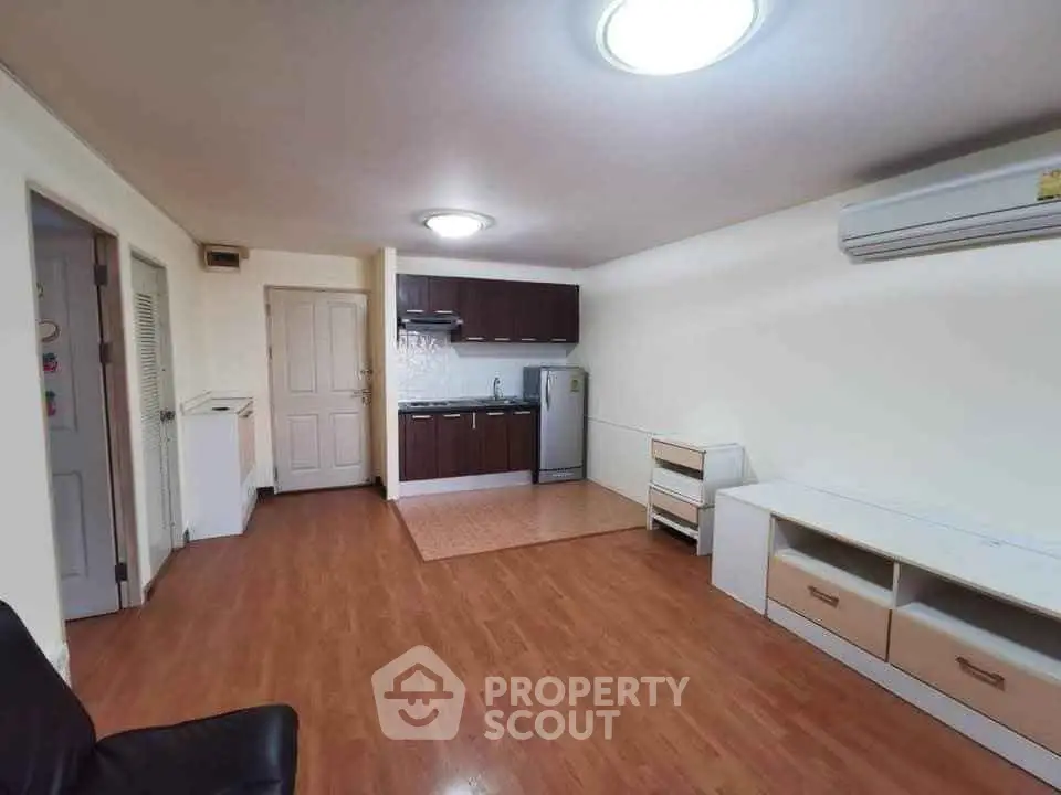 Spacious living room with open kitchen and wooden flooring in modern apartment.