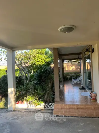 Charming garden view from a cozy patio with tiled flooring and lush greenery.