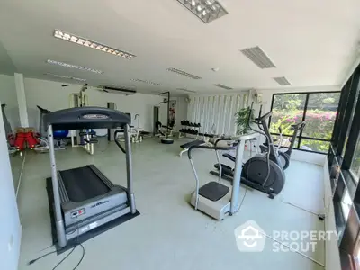 Spacious gym with modern equipment and large windows offering natural light