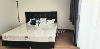 Modern bedroom with stylish bed and floor lamp, featuring elegant curtains and wooden flooring.