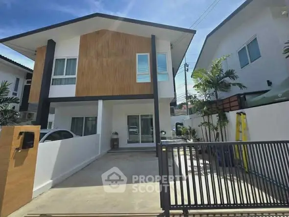 Modern two-story house with wooden facade and gated driveway