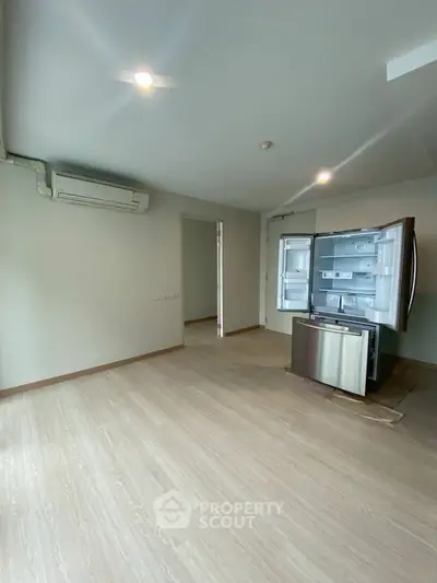 Spacious unfurnished room with modern refrigerator and air conditioning